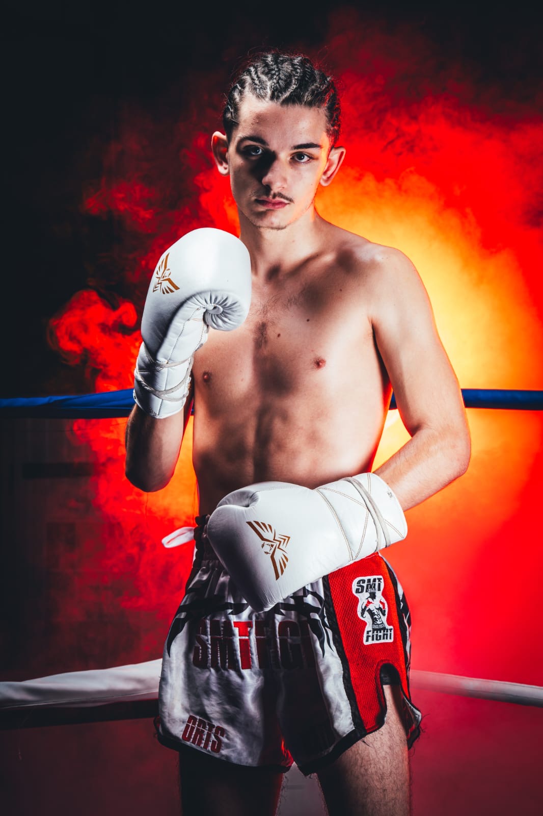 Photo de Nathan dans le ring portant ses gants de boxe et levant le poing à hauteur de visage